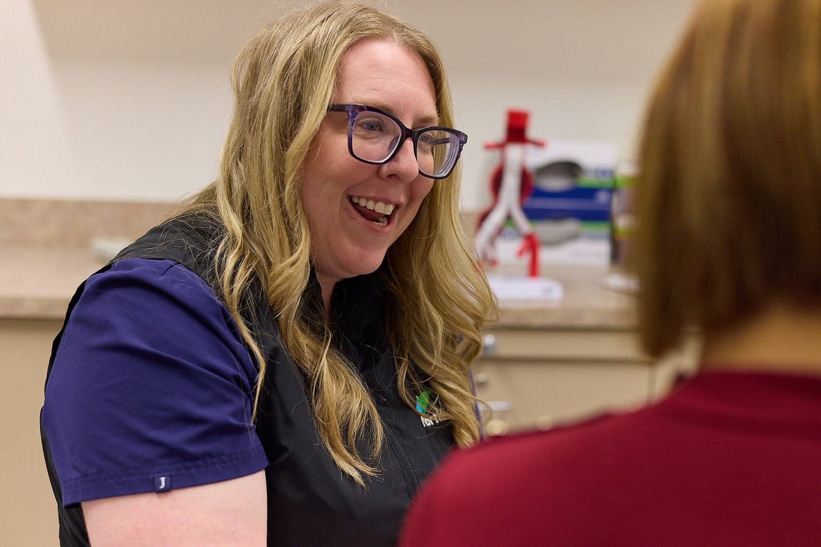 A smiling Northbay Health team member talks with a patient in an exam room.