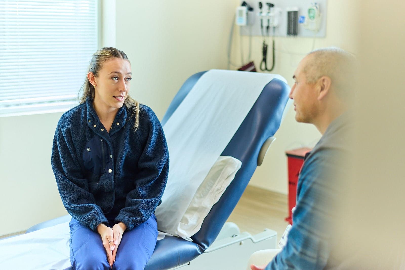 A patient seated on an exam table talks with a Northbay Health team member in an exam room.