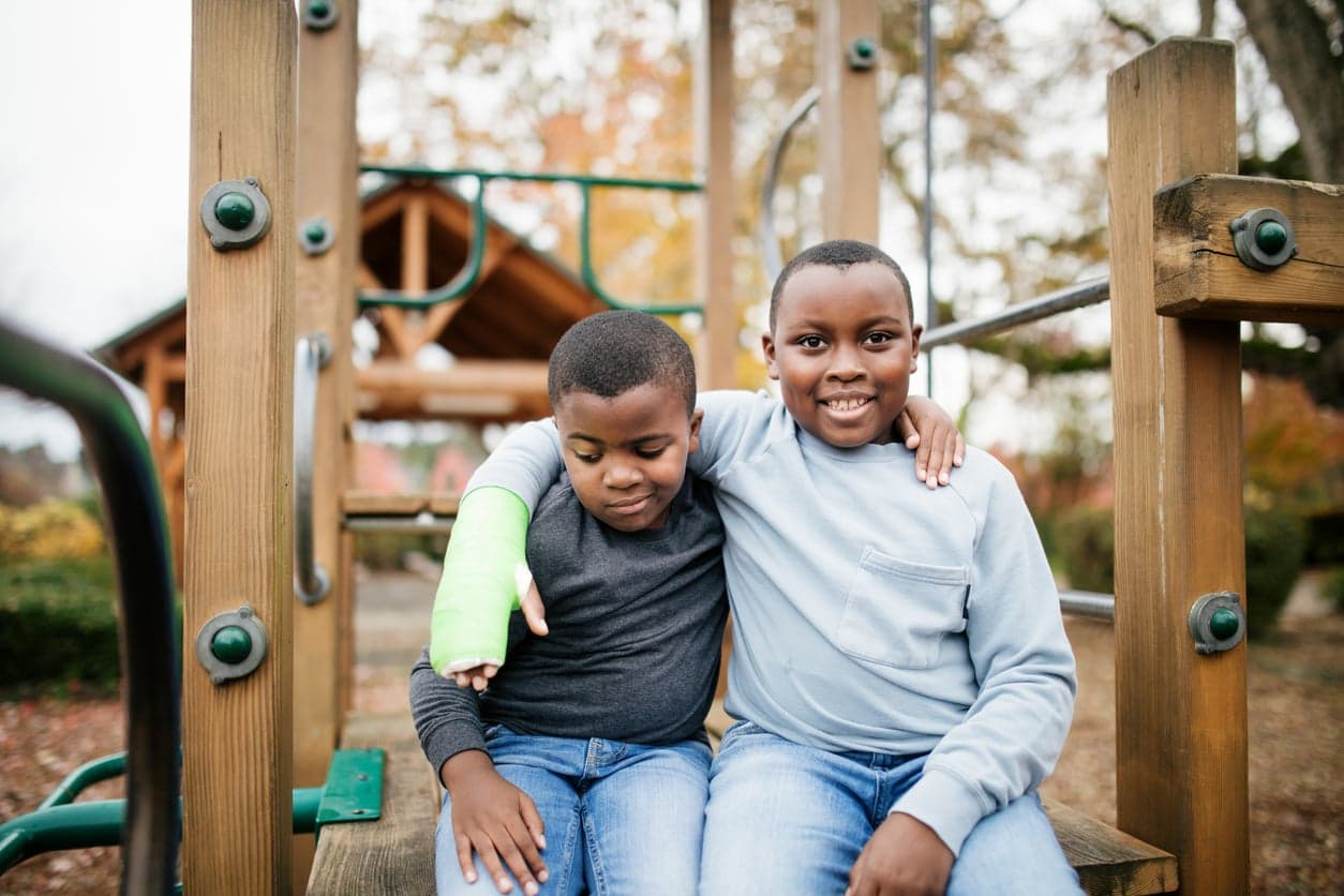 Two boys on the playground, one has a broken arm