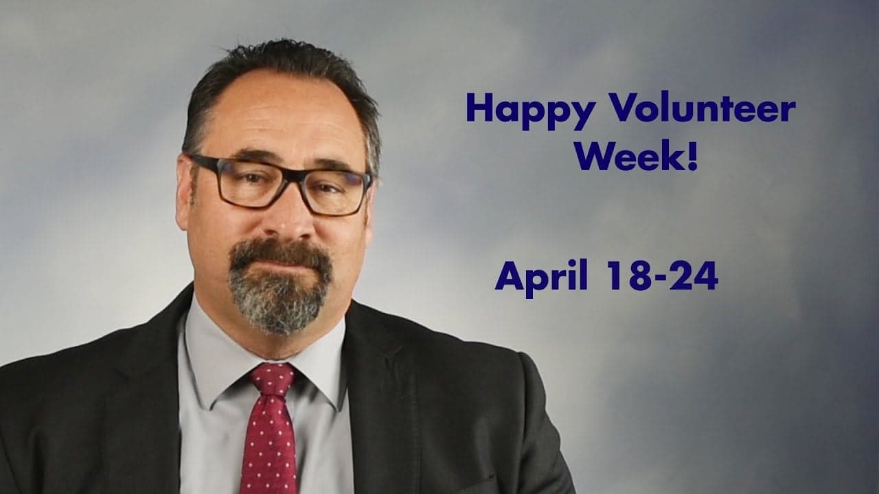 Man wearing glasses and burgundy tie with text reading "Happy Volunteer Week! April 18-24"