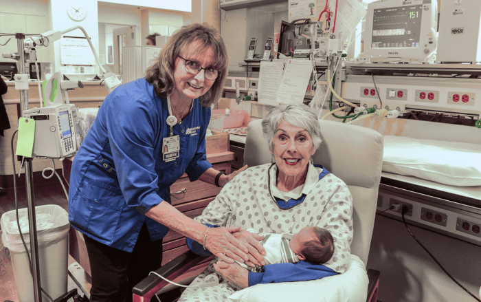 Retired Northbay Health employee and now volunteer Diane Harris (left), who helped launch the NICU Cuddler program, helps volunteer Gayle Ratliff get settled in for a soothing session with little Wyatt Brenner.