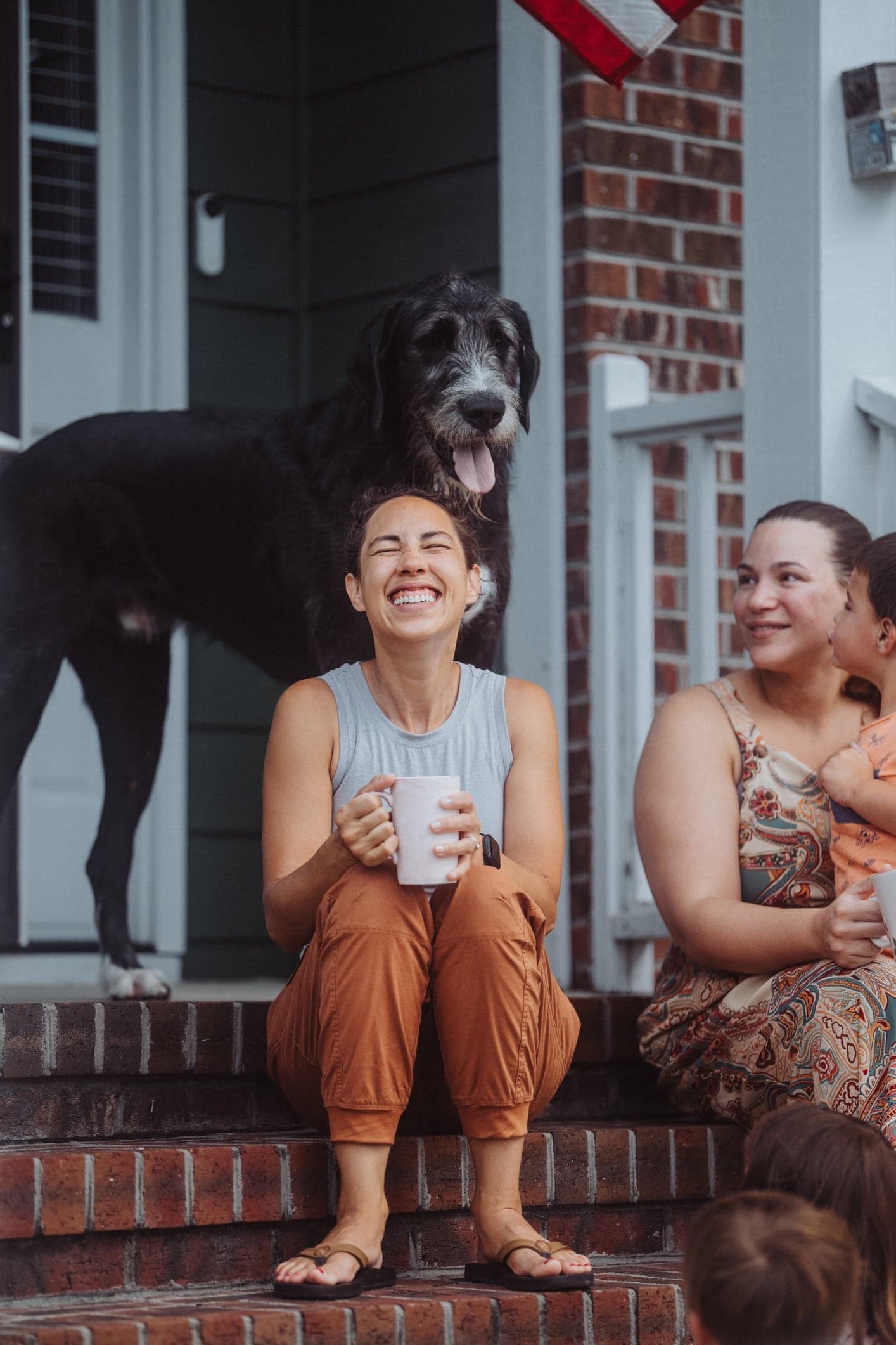 Two women and a dog sit on a porch