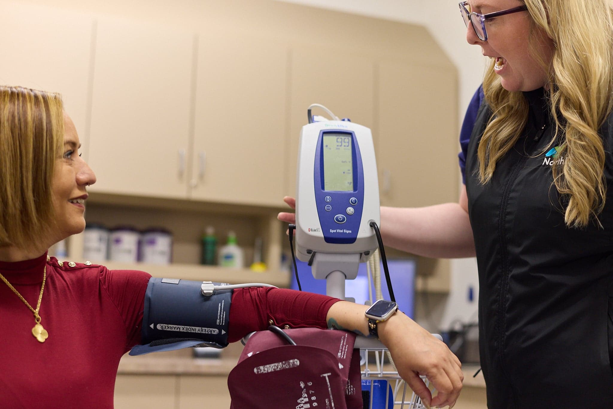 A Northbay Health team member takes a woman’s blood pressure with an arm cuff and monitor.