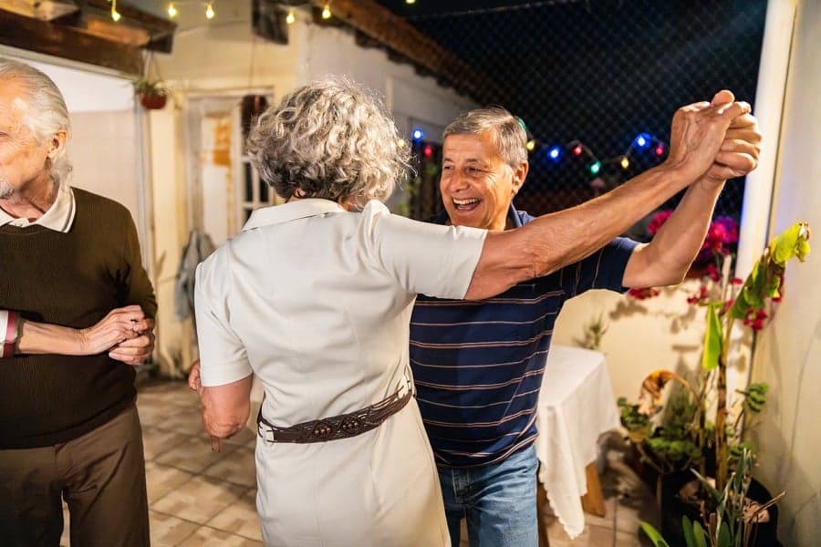 A middle aged couple dances while smiling