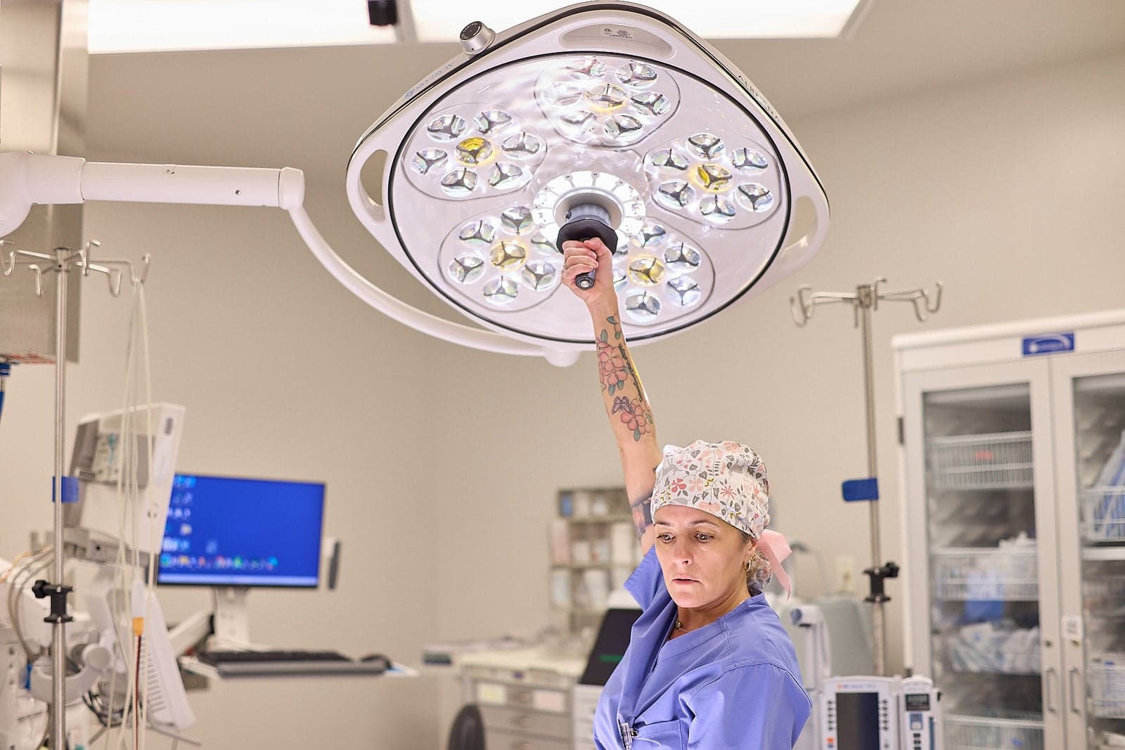 A female medical professional adjusts the lights in an operating room.