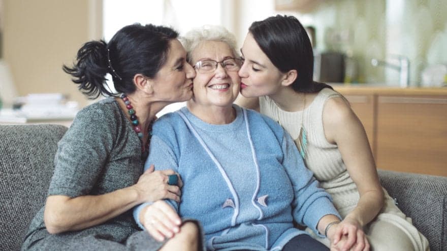 Three generations of women hugging and sharing a sweet moment together in the family's living room.