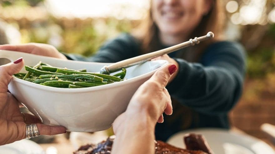 Family members passing a dish of green beans around the table.