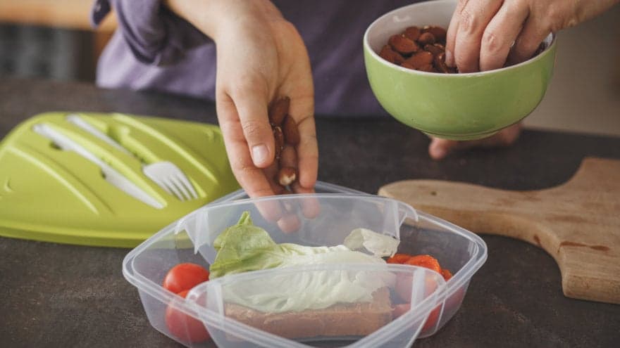 Parent and child working together to put together snacks in a multiple-compartment lunchbox.