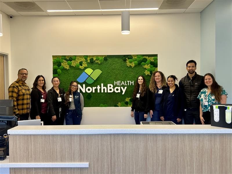 NorthBay Health staff in front of the NorthBay Health logo moss wall that welcomes visitors to our Primary and Urgent Care in Winters, CA.