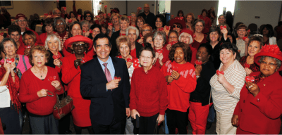 Dr. Beygui, cardiologist, stands in front of the crowd of Luncheon attendees, holding their heart shaped ice packs.