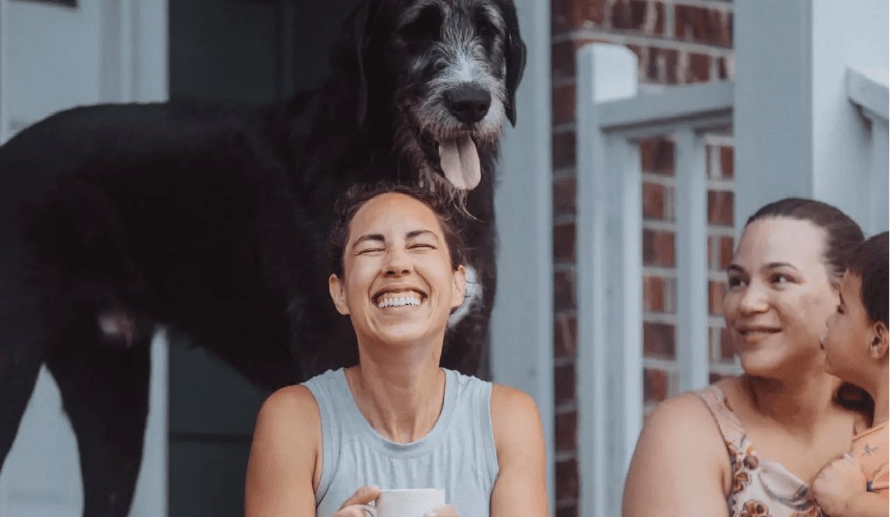 Two women and a dog sit on a porch